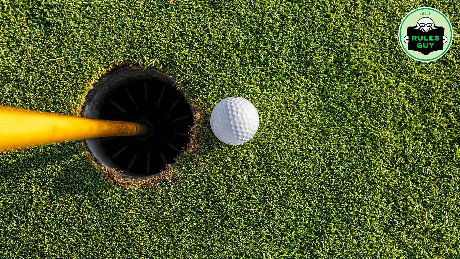 golf ball next to golf hole and flagstick on golf course