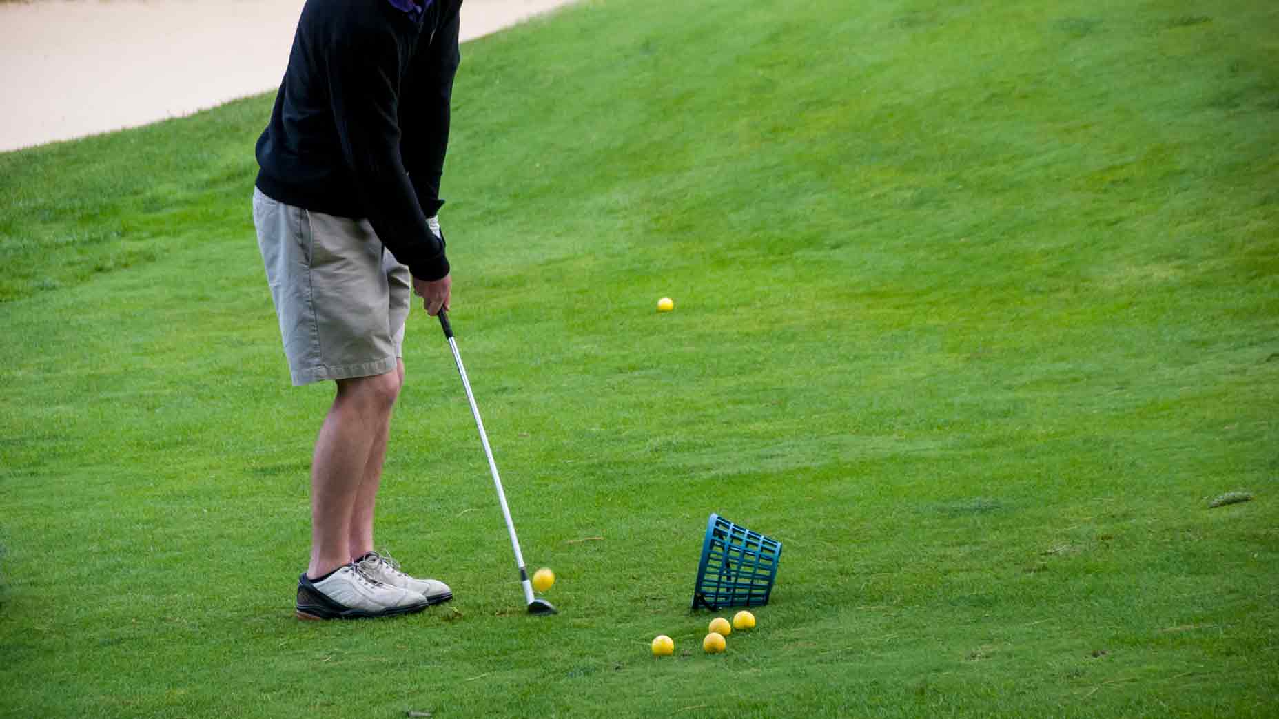 A golfer works on his chipping at a golf course practice range on a late spring day.