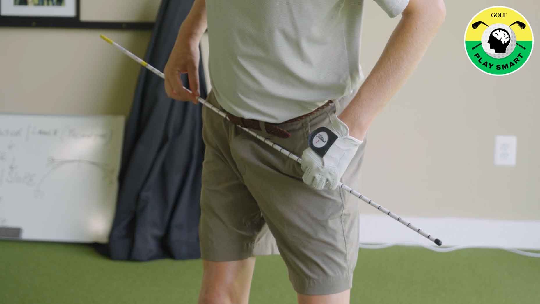 golfer turns hips back with alignment stick through the belt loops